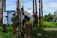 Petugas menertibkan atribut promosi yang dinilai merusak estetika kota di kawasan Kelurahan Aie Pacah, Senin (6/4/2026). (Foto: Diskominfo Padang)