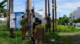 Petugas menertibkan atribut promosi yang dinilai merusak estetika kota di kawasan Kelurahan Aie Pacah, Senin (6/4/2026). (Foto: Diskominfo Padang)