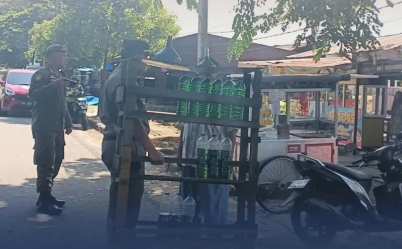 Petugas Satpol PP Padang menertibkan lapak pedagang minyak eceran yang memanfaatkan badan jalan untuk berjualan, Senin (20/4/2026). (Foto: Humas Satpol PP Padang)
