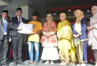 Pj. Sekda Padang Pariaman Hendra Aswara menyerahkan penghargaan bupati kepada Kadri Maiwansyah dalam upacara peringatan Hari Otonomi Daerah dan Hardiknas di halaman Kantor Bupati, Senin (4/5/2026). (Foto: Diskominfo Padang Pariaman)