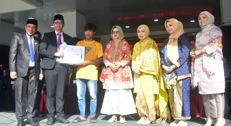 Pj. Sekda Padang Pariaman Hendra Aswara menyerahkan penghargaan bupati kepada Kadri Maiwansyah dalam upacara peringatan Hari Otonomi Daerah dan Hardiknas di halaman Kantor Bupati, Senin (4/5/2026). (Foto: Diskominfo Padang Pariaman)