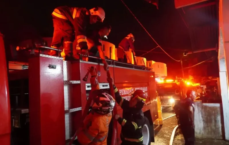 Petugas Damkar Padang Panjang berupaya memadamkan api yang menghanguskan satu unit mobil dan merusak sebagian rumah warga di kawasan Silaing Bawah, Kamis malam (28/5/2026). (Foto: Diskominfo Padang Panjang)