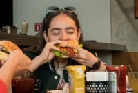 Ilustrasi seorang wanita makan burger. (Foto: Pexels)