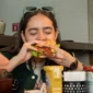 Ilustrasi seorang wanita makan burger. (Foto: Pexels)