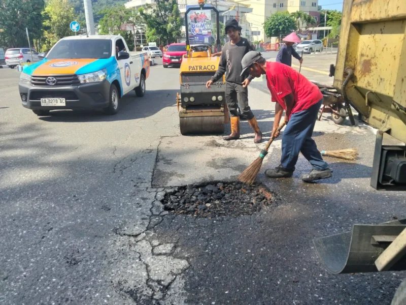 Pekerja Dinas PUPR Padang sedang melakukan penambalan jalan berlubang. (Foto: Pemko Padang)