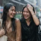Ilustrasi dua orang wanita berjalan di tengah hujan. (Foto: AI Generate)