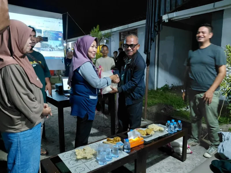 Kepala Dinas Perkim Padang Tri Hadiyanto menyerahkan bantuan beras kepada warga Huntara Lubuk Buaya. (Foto: Pemko Padang)