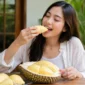 Ilustrasi seorang wanita sedang menikmati durian. (Foto: AI Generate)