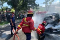 Petugas Damkar Padang memadamkan api yang membakar mobil Honda Freed di depan McDonald's Ahmad Yani Padang, Jumat (24/7/2026). (Foto: Dinas Damkar Padang)