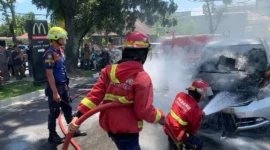 Petugas Damkar Padang memadamkan api yang membakar mobil Honda Freed di depan McDonald's Ahmad Yani Padang, Jumat (24/7/2026). (Foto: Dinas Damkar Padang)