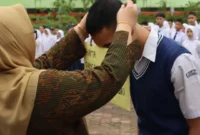 Kepala SMK SMAK Padang, Silvania Lorina memasangkan kokarde kepada peserta tanda dibukanya MPLS, Kamis (9/7). (Foto: Humas SMK SMAK Padang)