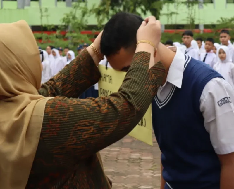 Kepala SMK SMAK Padang, Silvania Lorina memasangkan kokarde kepada peserta tanda dibukanya MPLS, Kamis (9/7). (Foto: Humas SMK SMAK Padang)