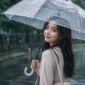 Ilustrasi seorang wanita menggunakan payung saat berjalan di tengah hujan. (Foto: AI Generate)