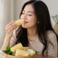 Ilustrasi wanita menikmati singkong rebus. (Foto: AI Generate)