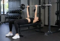 Ilustrasi seorang wanita melakukan latihan bench press di pusat kebugaran. (Foto: AI Generate)