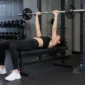 Ilustrasi seorang wanita melakukan latihan bench press di pusat kebugaran. (Foto: AI Generate)