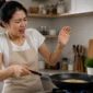Ilustrasi wanita terkena percikan minyak panas saat memasak. (Foto: AI Generate)