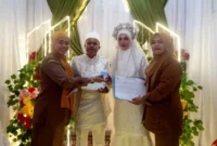 Kabid Pelayanan Pendaftaran Penduduk Dinas Dukcapil Pesisir Selatan, Anfebrianita (kiri) saat menyerahkan KK dan KTP-el kepala Rizal dan Vela. (Foto: Dok. Niks)