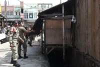 Personel Satpol PP Padang menertibkan bangle yang berdiri di atas fasilitas drainase di Jalan HOS Cokroaminoto, Kelurahan Berok Nipah, Sabtu (22/8/2026). (Foto: Satpol PP Padang)