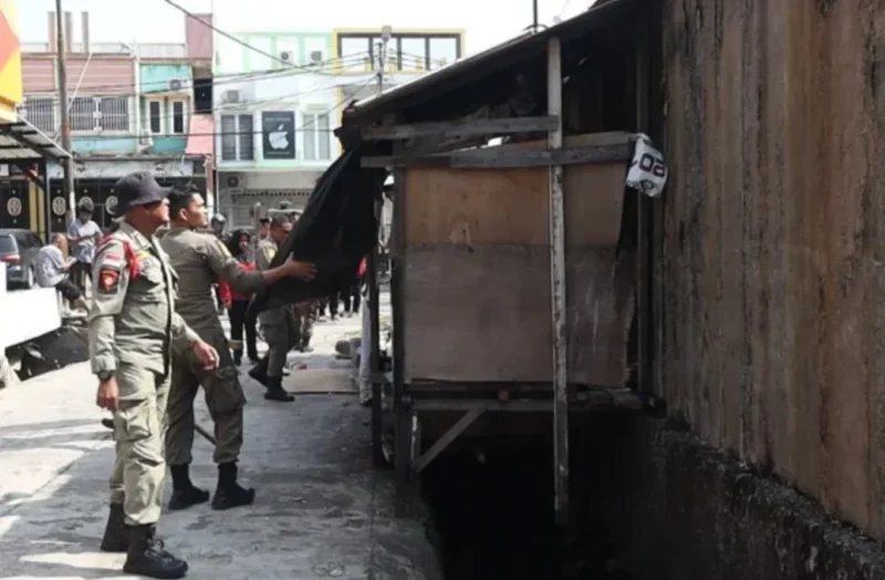 Personel Satpol PP Padang menertibkan bangle yang berdiri di atas fasilitas drainase di Jalan HOS Cokroaminoto, Kelurahan Berok Nipah, Sabtu (22/8/2026). (Foto: Satpol PP Padang)