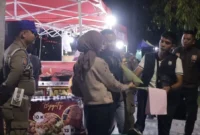 Petugas Satpol PP Padang memberikan surat teguran dan pemahaman secara persuasif kepada PKL yang berjualan di atas trotoar kawasan Batang Arau, Sabtu malam (22/8/2026). (Foto: Dok. Humas Satpol PP Padang)