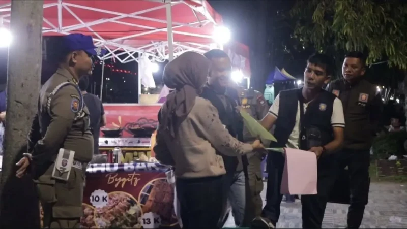 Petugas Satpol PP Padang memberikan surat teguran dan pemahaman secara persuasif kepada PKL yang berjualan di atas trotoar kawasan Batang Arau, Sabtu malam (22/8/2026). (Foto: Dok. Humas Satpol PP Padang)
