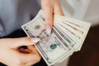 Ilustrasi seorang wanita memegang uang dolar AS. (Foto: Pexels)
