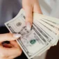 Ilustrasi seorang wanita memegang uang dolar AS. (Foto: Pexels)
