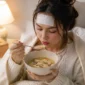 Ilustrasi seorang wanita yang sedang mengalami demam mengonsumsi sup ayam. (Foto: AI Generate)