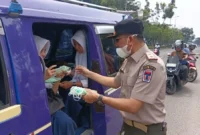 Kepala Pelaksana BPBD Padang, Hendri Zulviton membagikan masker kepada penumpang angkot. (Foto: BPBD Padang)