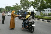 Asisten III Setdako Padang Corri Saidan bersama Kepala BPBD Padang Hendri Zulviton membagikan masker kepada pengendara. (Foto: Pemko Padang)