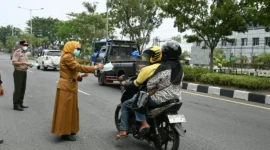 Asisten III Setdako Padang Corri Saidan bersama Kepala BPBD Padang Hendri Zulviton membagikan masker kepada pengendara. (Foto: Pemko Padang)