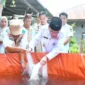 Wakil Wali Kota Padang, Maigus Nasir menebarkan bibit ikan saat meresmikan Kampung Budi Daya Ikan Air Tawar di kawasan Koto Parak, Jalan Djamaluddin Wak Ketok, Kelurahan Pisang, Kecamatan Pauh, Rabu (28/10/2026). (Foto: Pemko Padang)