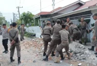 Petugas Satpol PP Padang membongkar pagar rumah warga yang memakan sebagian badan jalan di kawasan Dadok Tunggul Hitam, Jumat (2/10/2026). (Foto: Humas Satpol PP Padang)